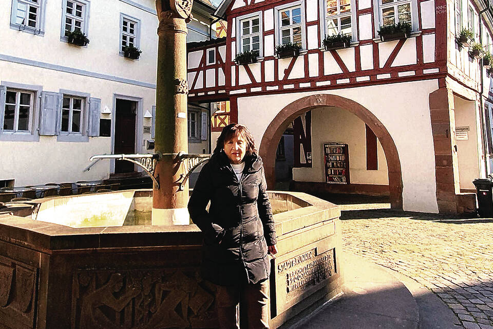 Stadtführerin Romy Schilling am Schriesheimer Stadtbrunnen. Hinten rechts ist das Alte Rathaus zu sehen, links daneben das Stadtarchiv. Foto: Dorn