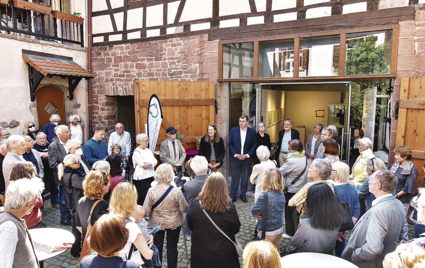„Debüt als Bürgermeister im Museum“: Christoph Oeldorf (links im Museumseingang) hielt vor etwa 60 Menschen die Laudatio zu der Ausstellung „simple present“, deren Gäste „einfach dabei“ sein sollen. Foto: Dorn